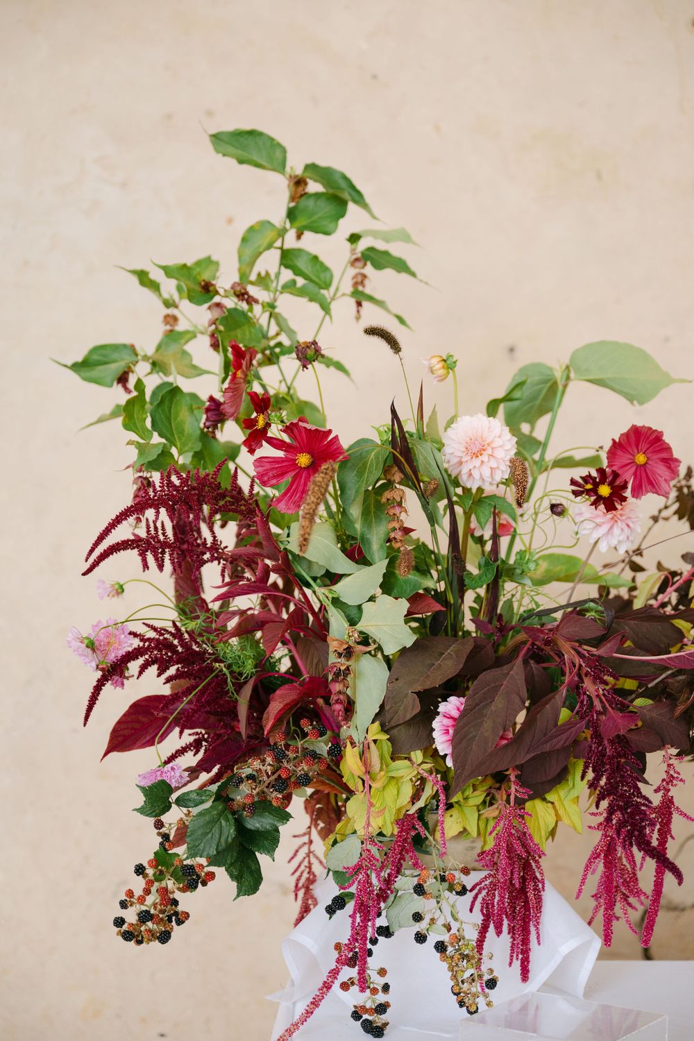 Stunning floral arrangement with deep red amaranth, pink roses, and green foliage.