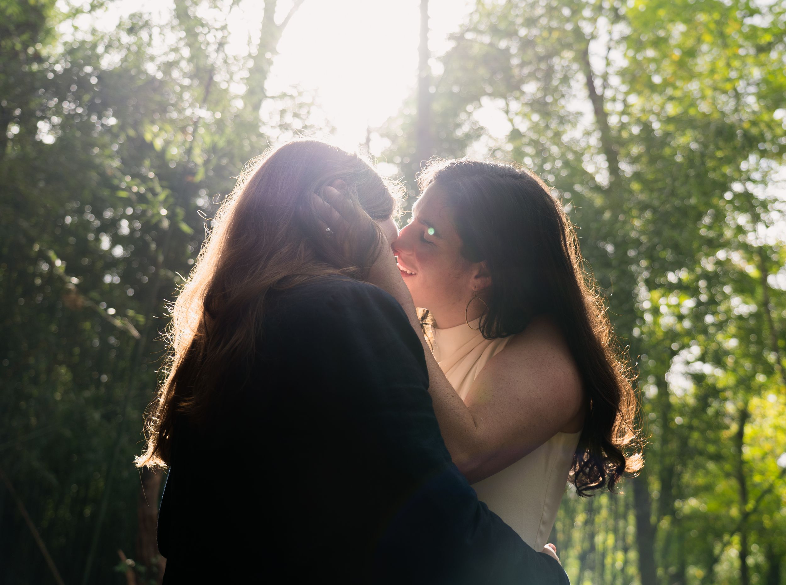 Editorial Image of lesbian wedding couple kissing with trees behind them