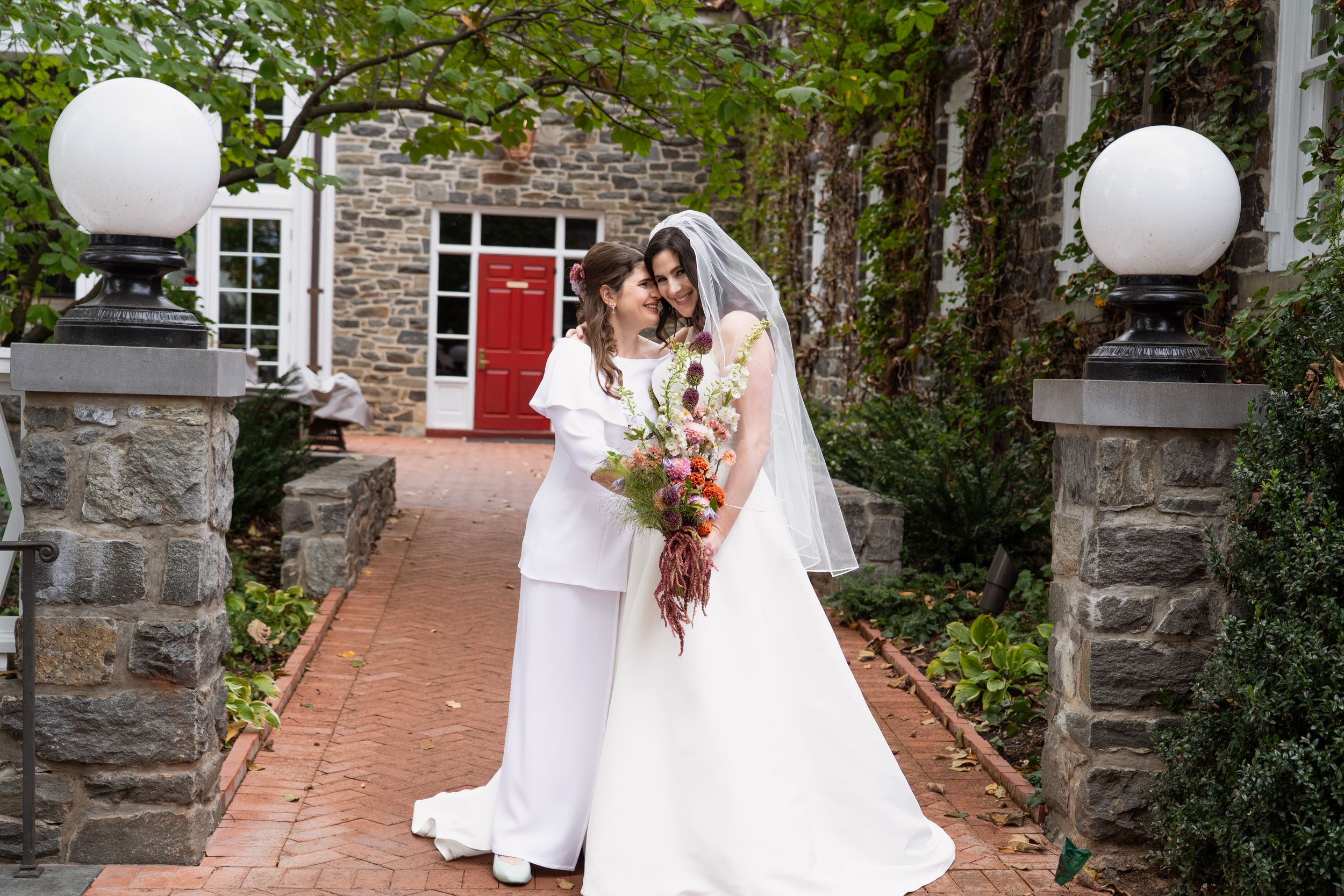 Editorial Image of lesbian wedding couple kissing with trees and an open gate behind them