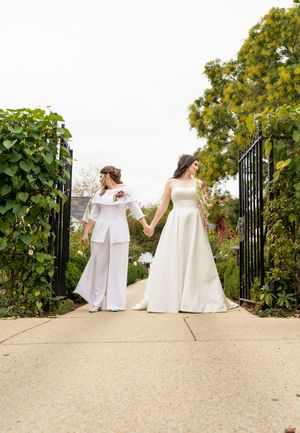 Editorial Image of lesbian wedding couple kissing with trees and an open fence gate behind them