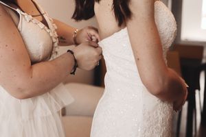 Manos ajustando vestido de novia bordado durante los preparativos, fotógrafa de boda en País Vasco