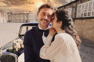 Pareja en atuendo de boda junto a coche clásico decorado, en calle empedrada al atardecer, fotógrafo boda en Alava