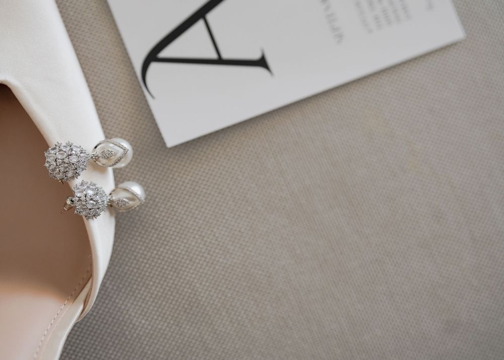 A collection of elegant silver and crystal bridal jewelry pieces arranged on a neutral textured background.