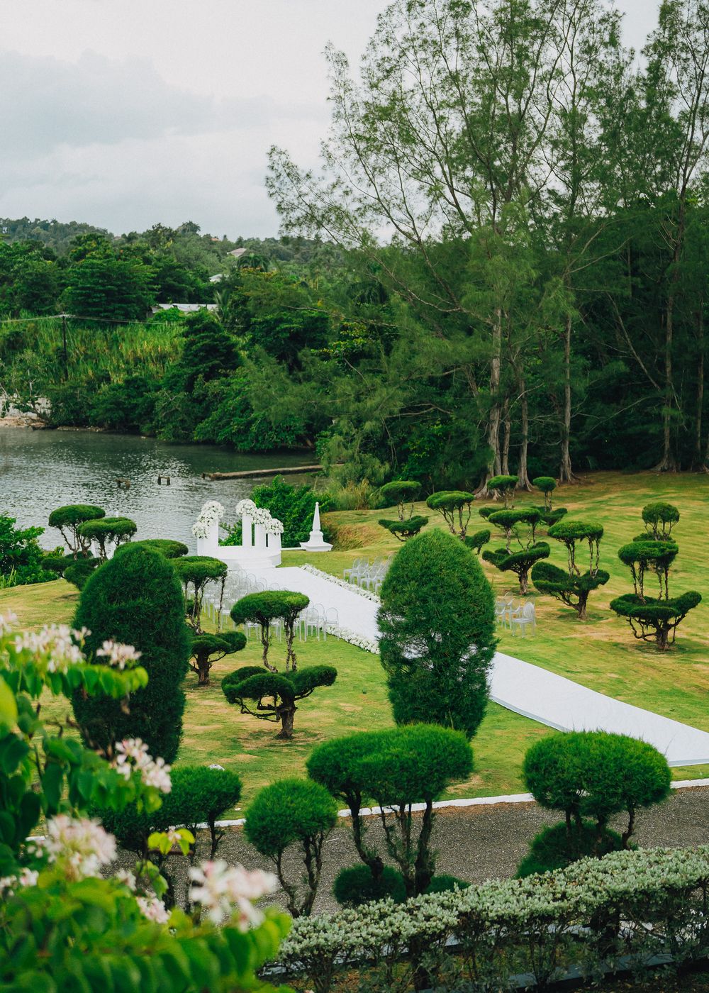 Landscaped garden with manicured topiary trees and winding pathways along a waterfront property.