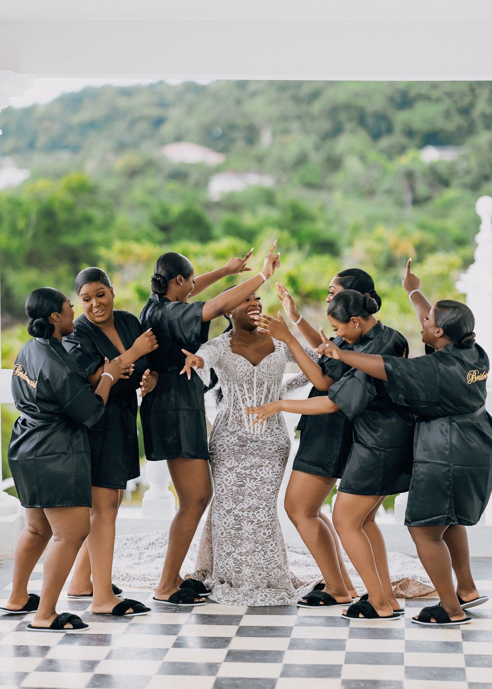 Wedding party in matching black outfits performs fun choreographed dance sequence on checkered floor.