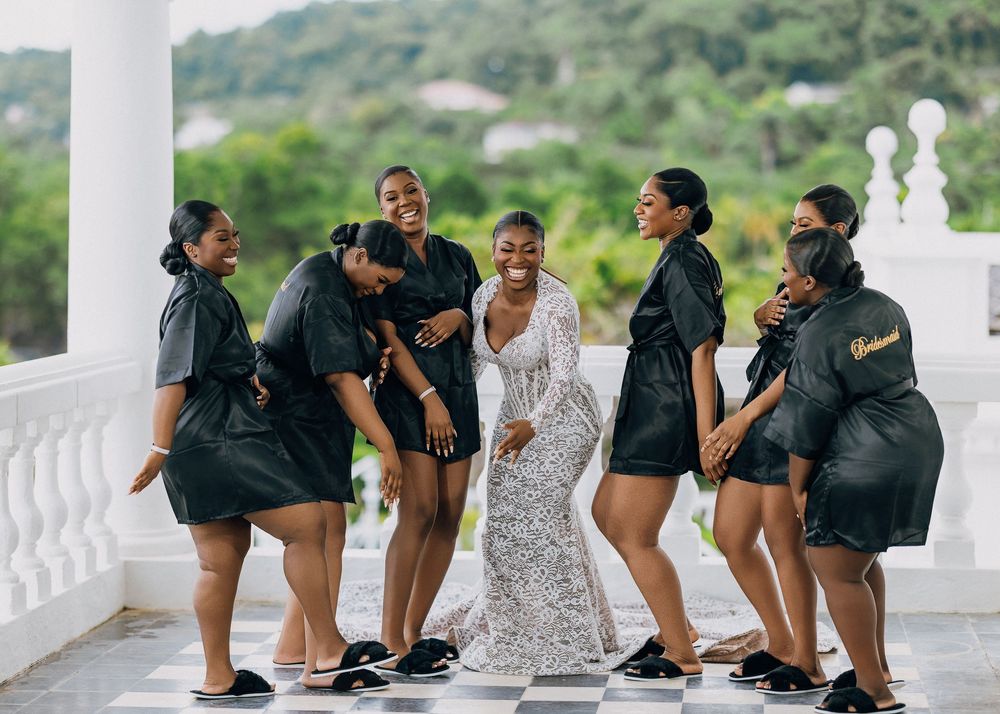 Candid shot of wedding party members in black and white outfits relaxing together outdoors.