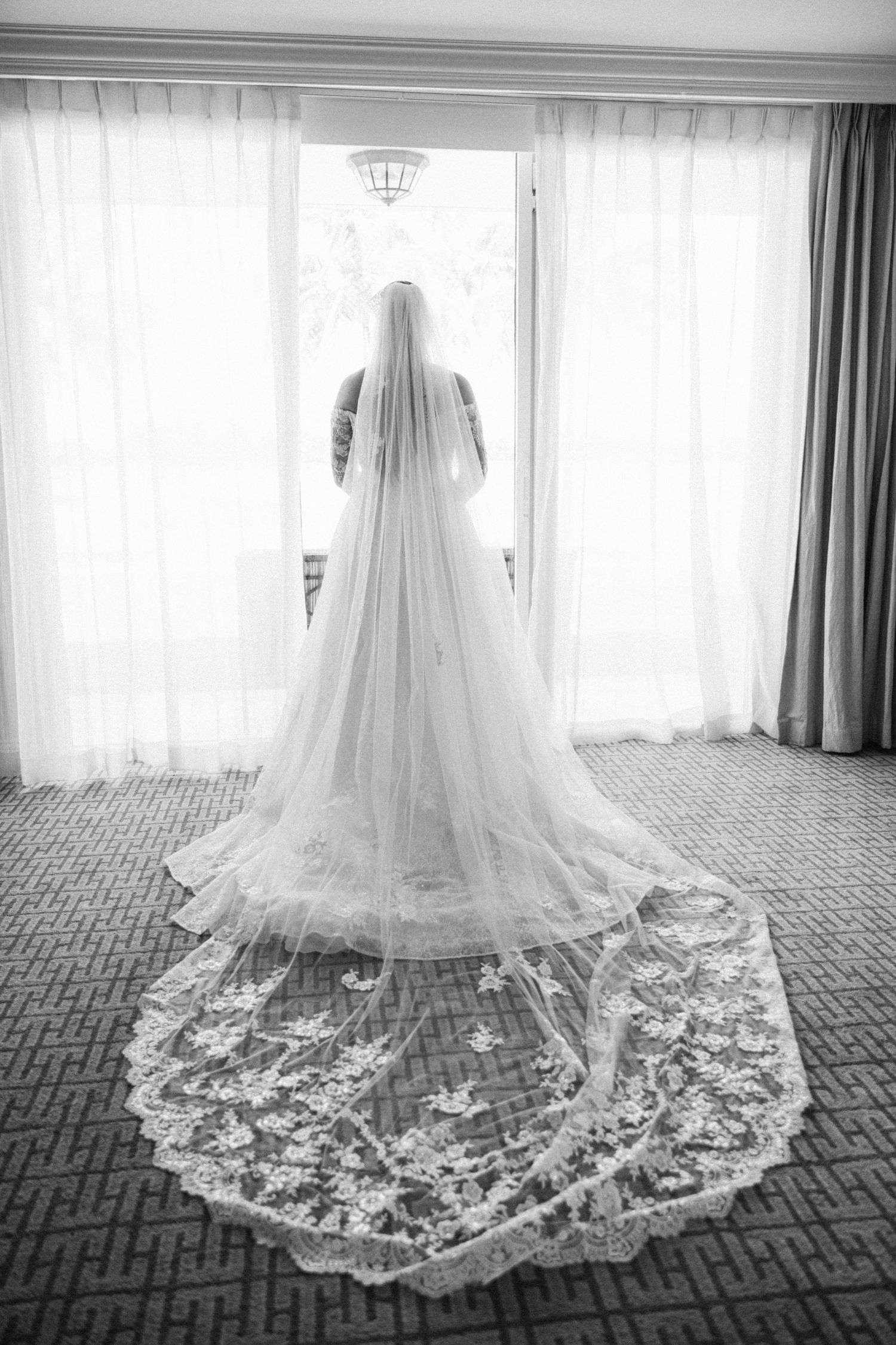 A series of black and white photos showing the intricate lace details of a wedding dress train spread across a patterned carpet.