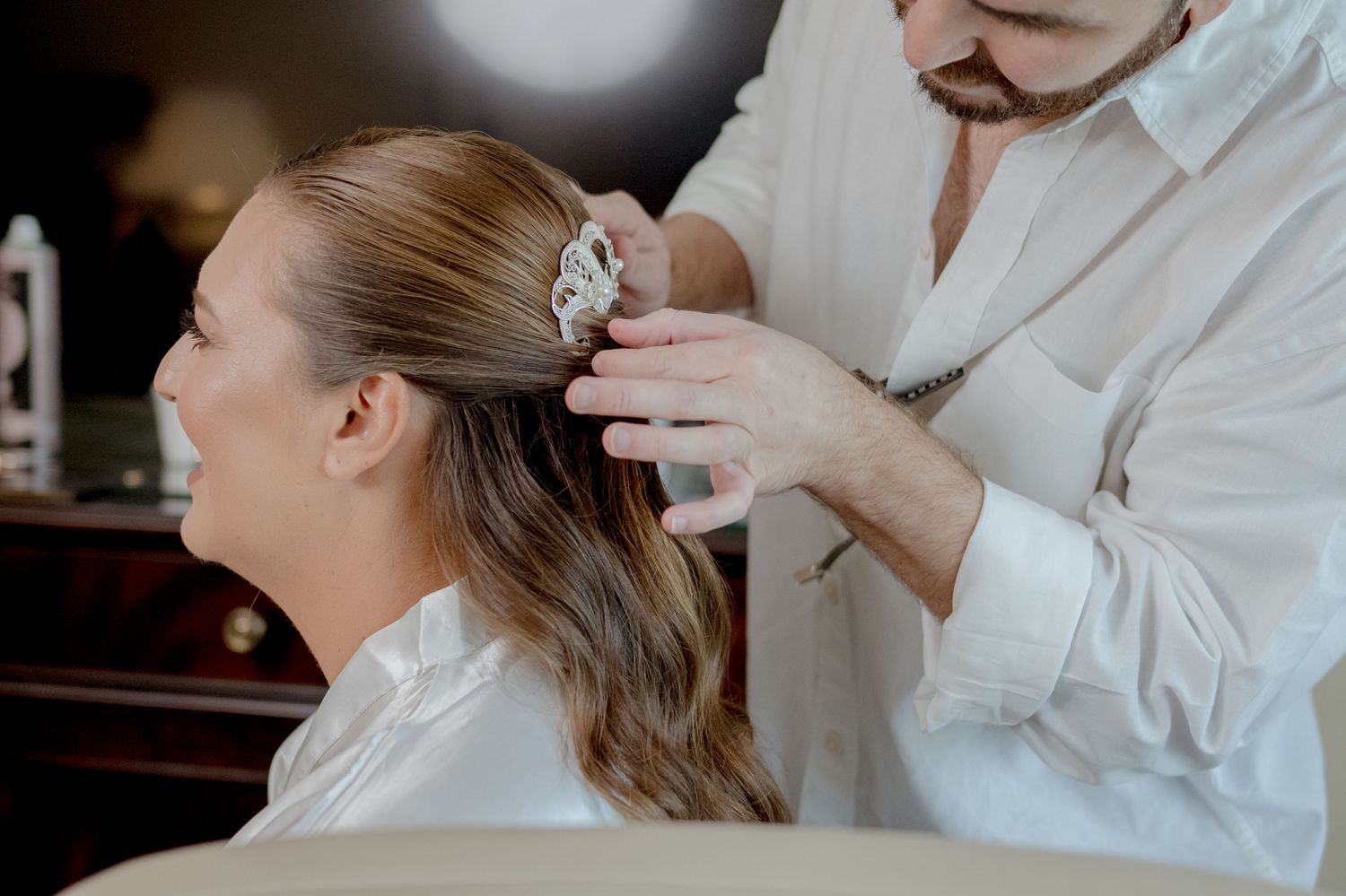 Hairstylist styling a bride's hair in preparation for a wedding ceremony.
