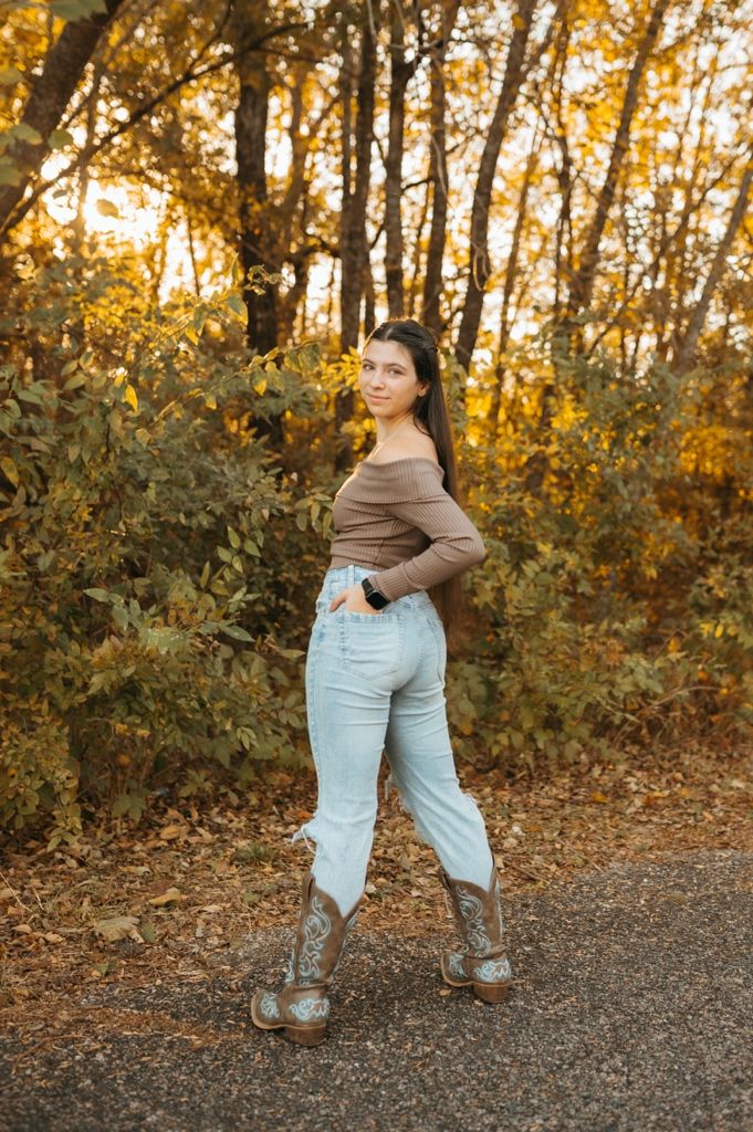 A casual autumn photoshoot on a gravel path with golden trees in the background.