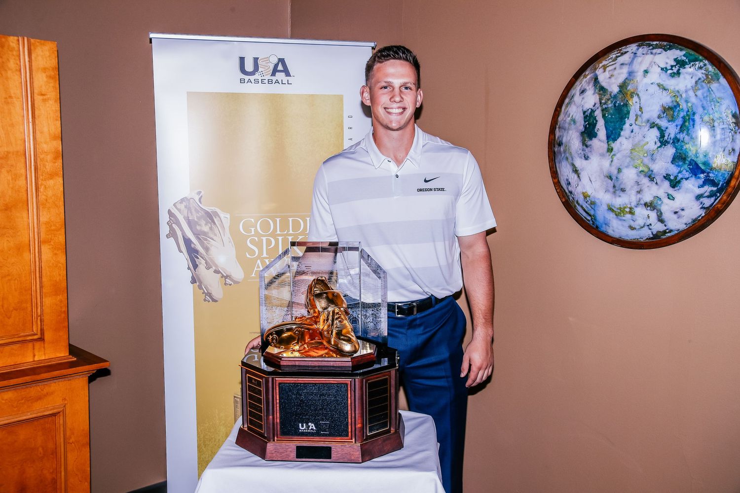 Young male athlete posing proudly with the prestigious USA Baseball Golden Spikes Award trophy.