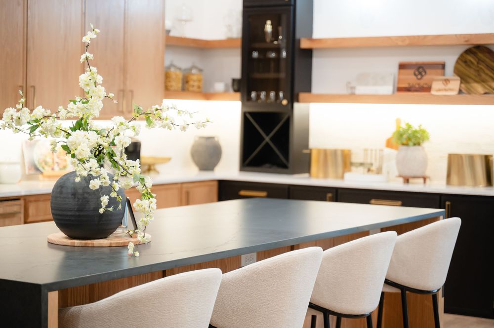Modern dining room interior with white chairs and black dining table illuminated by natural light from windows.