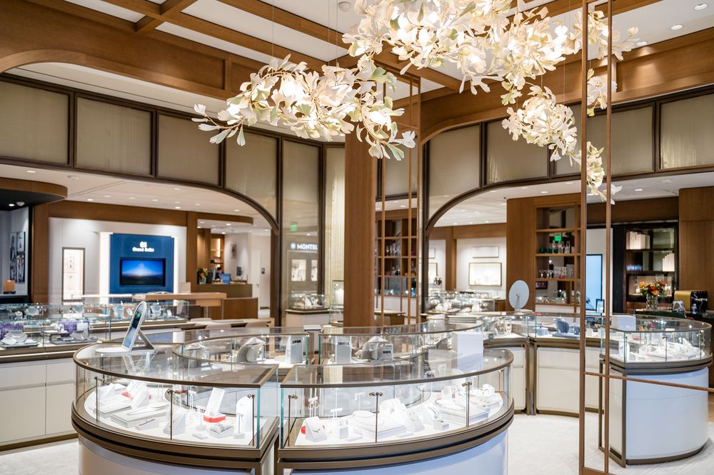 Elegant jewelry store interior with curved glass display cases, crystal chandeliers and warm wood accents throughout the showroom.