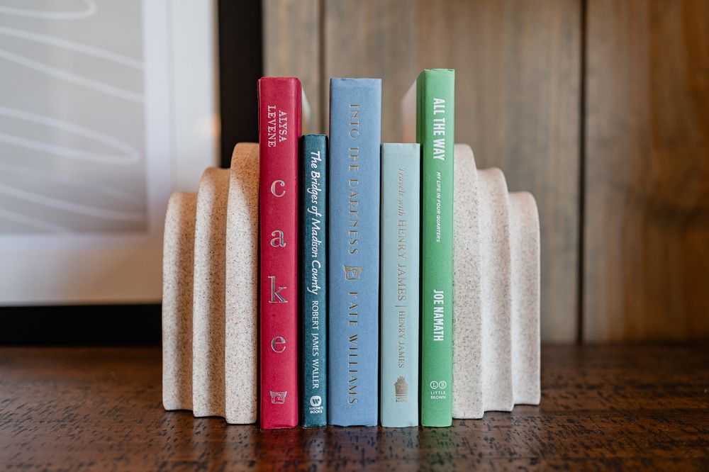A row of colorful vintage books arranged in ascending order on a wooden surface.