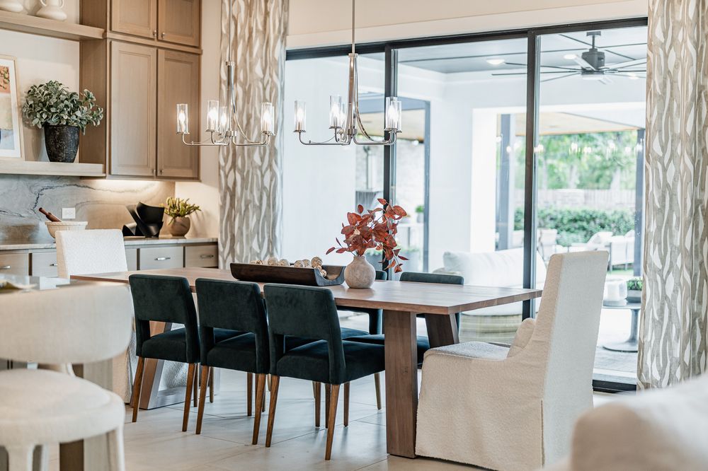 Modern restaurant interior with white columns, teal chairs, and elegant dining tables in a bright, airy space.