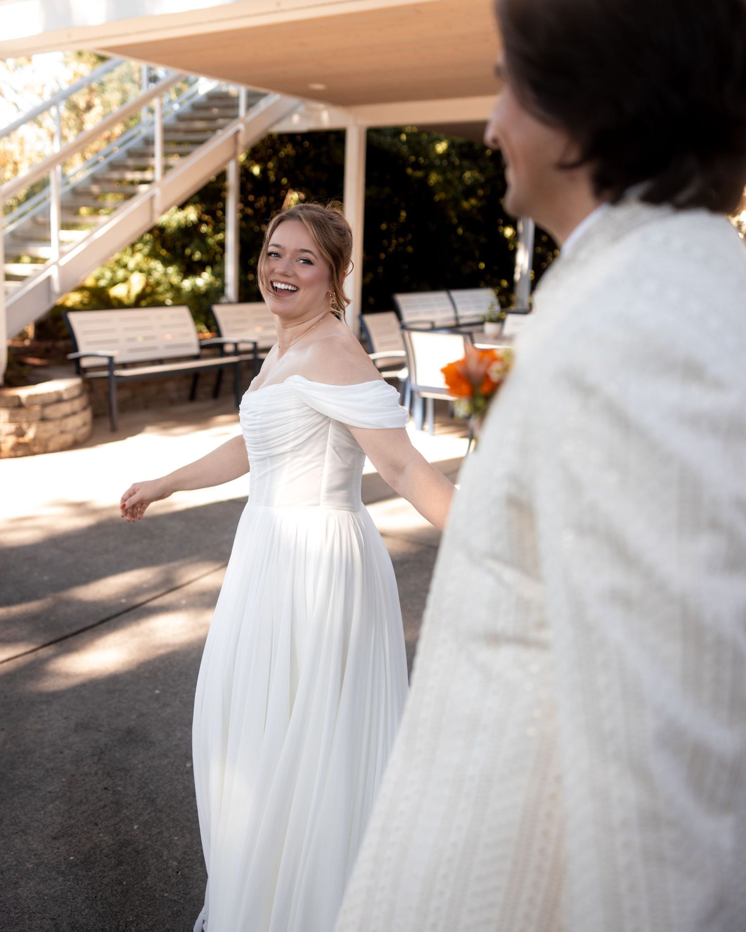 A joyful moment captured between newlyweds on an outdoor patio with dappled sunlight.