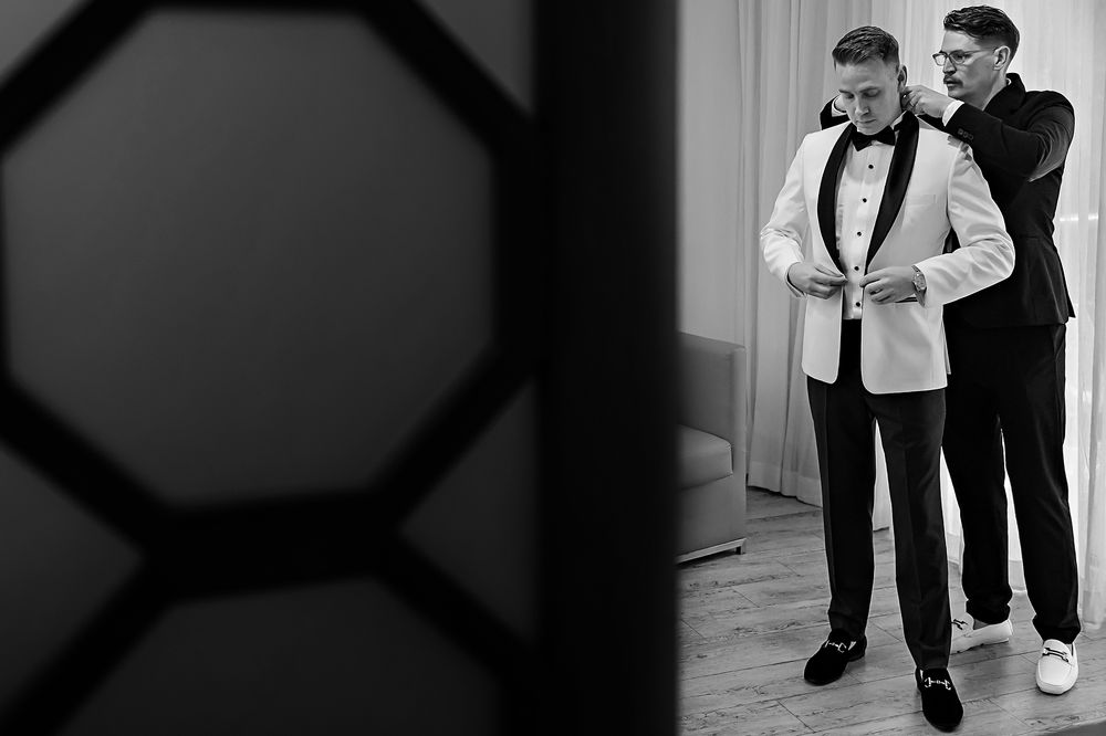 Groom and groomsman getting ready in black and white portrait.