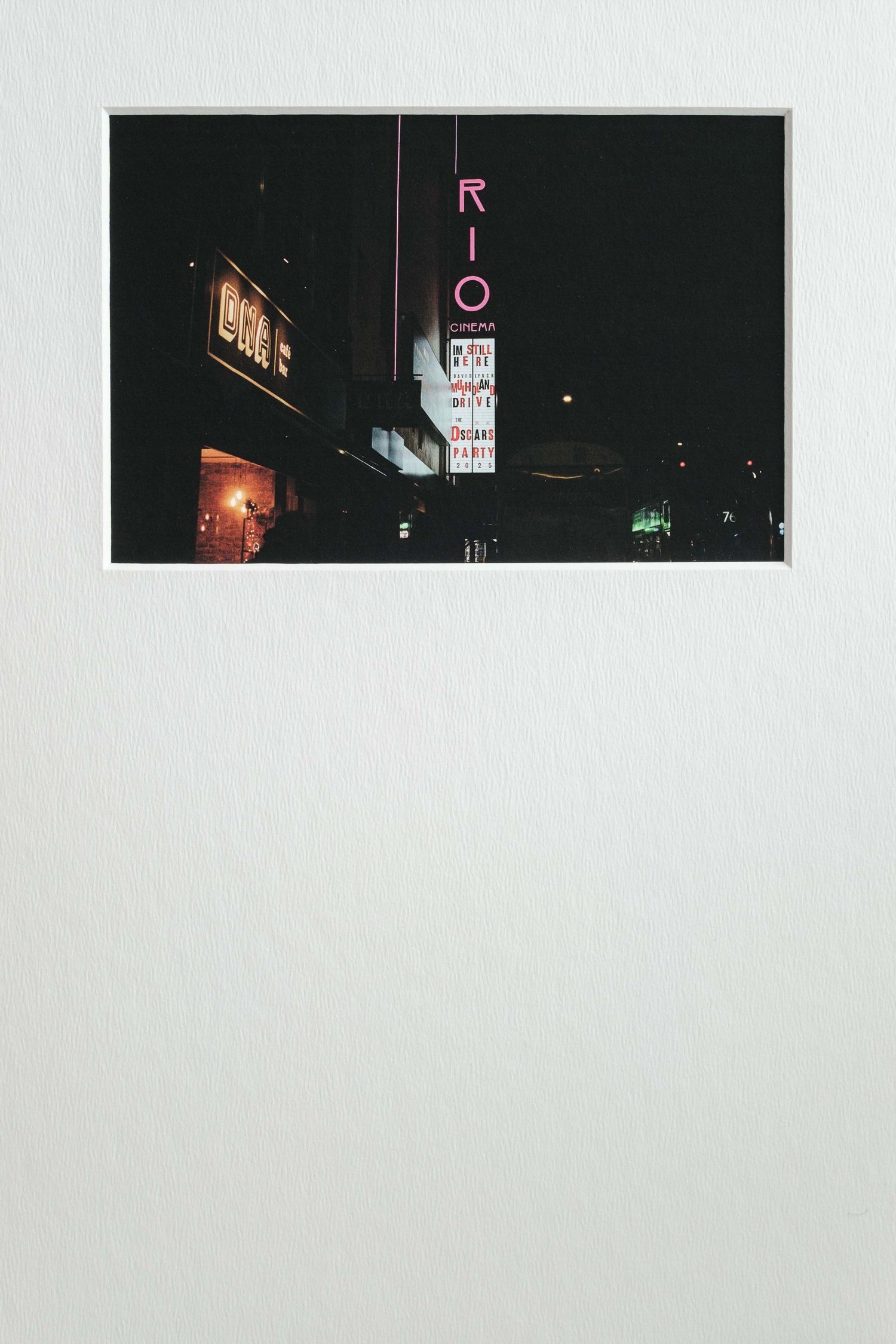 Dark urban nighttime scene with neon signs and city lights glowing against a black sky.