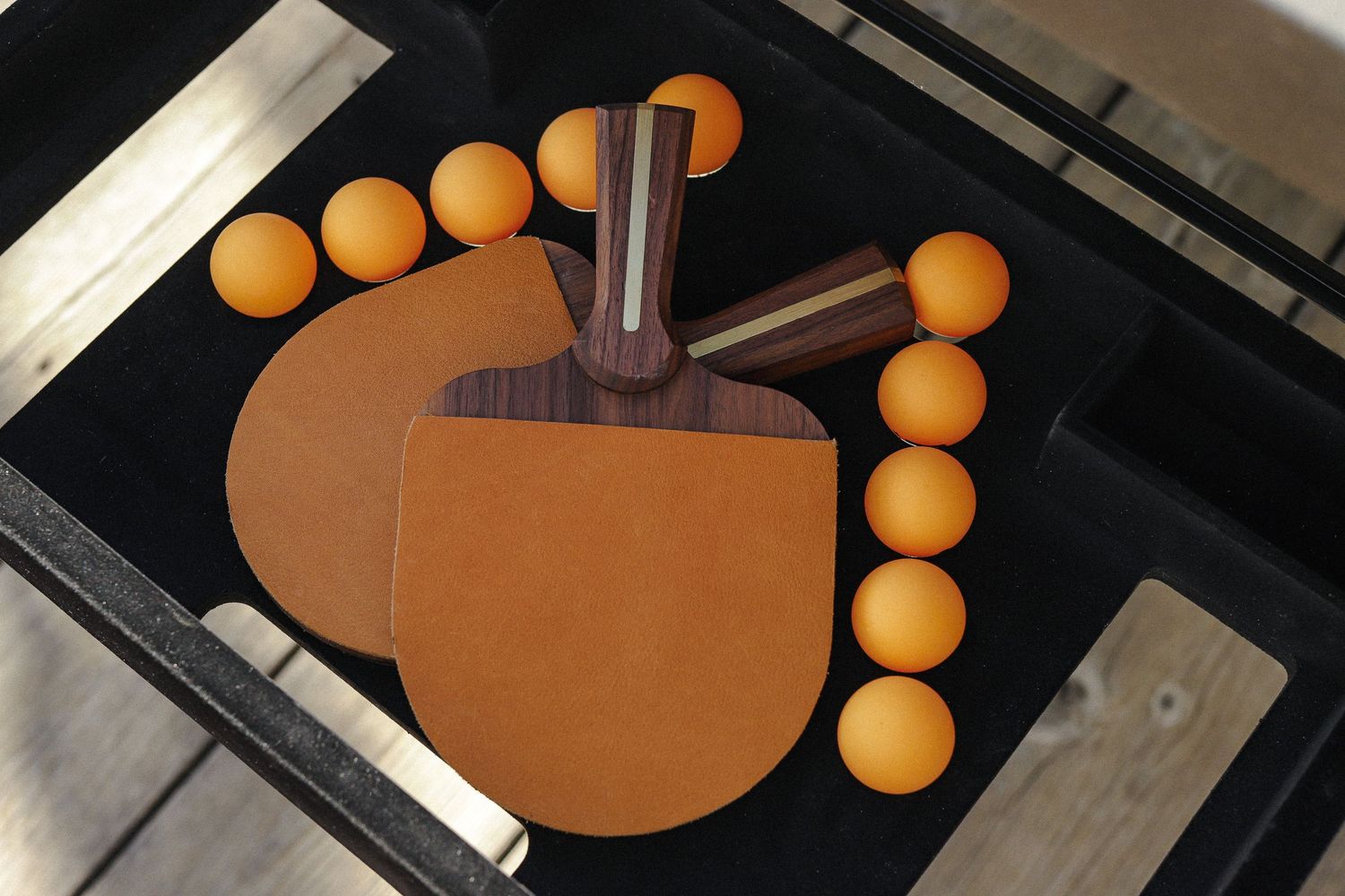 Orange magnetic balls arranged in a curved line pattern on a dark surface with metallic elements.