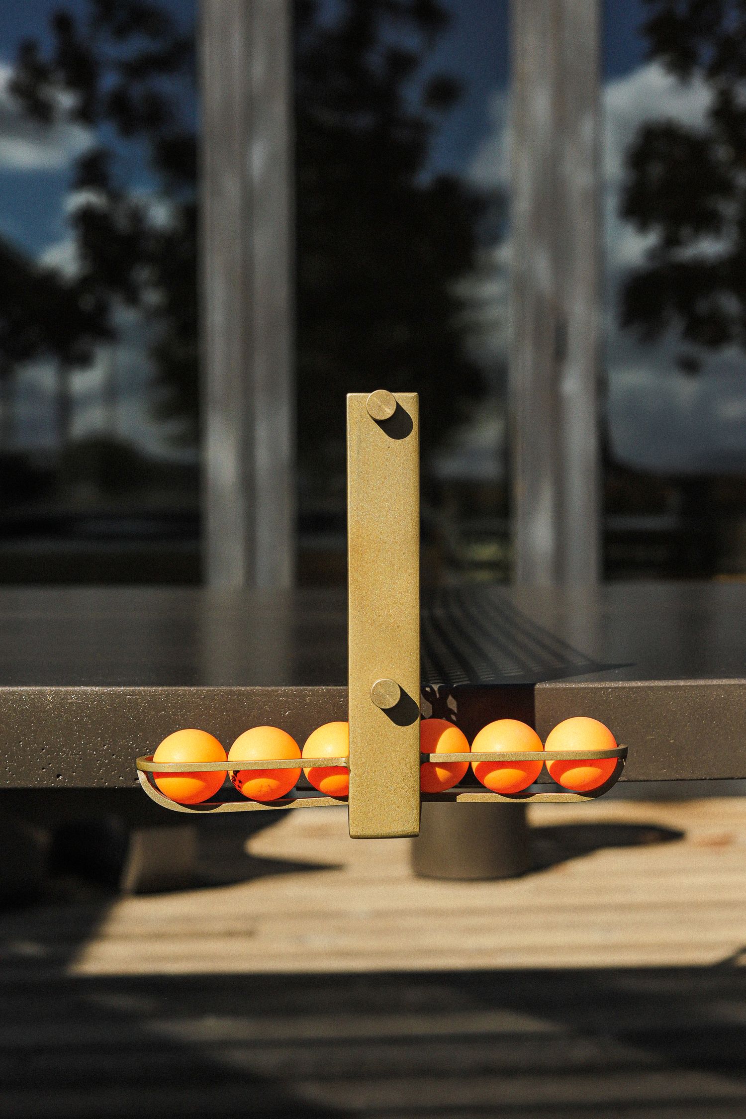 Row of oranges lined up against a vertical yellow beam casting dramatic shadows on a wooden surface in natural light.