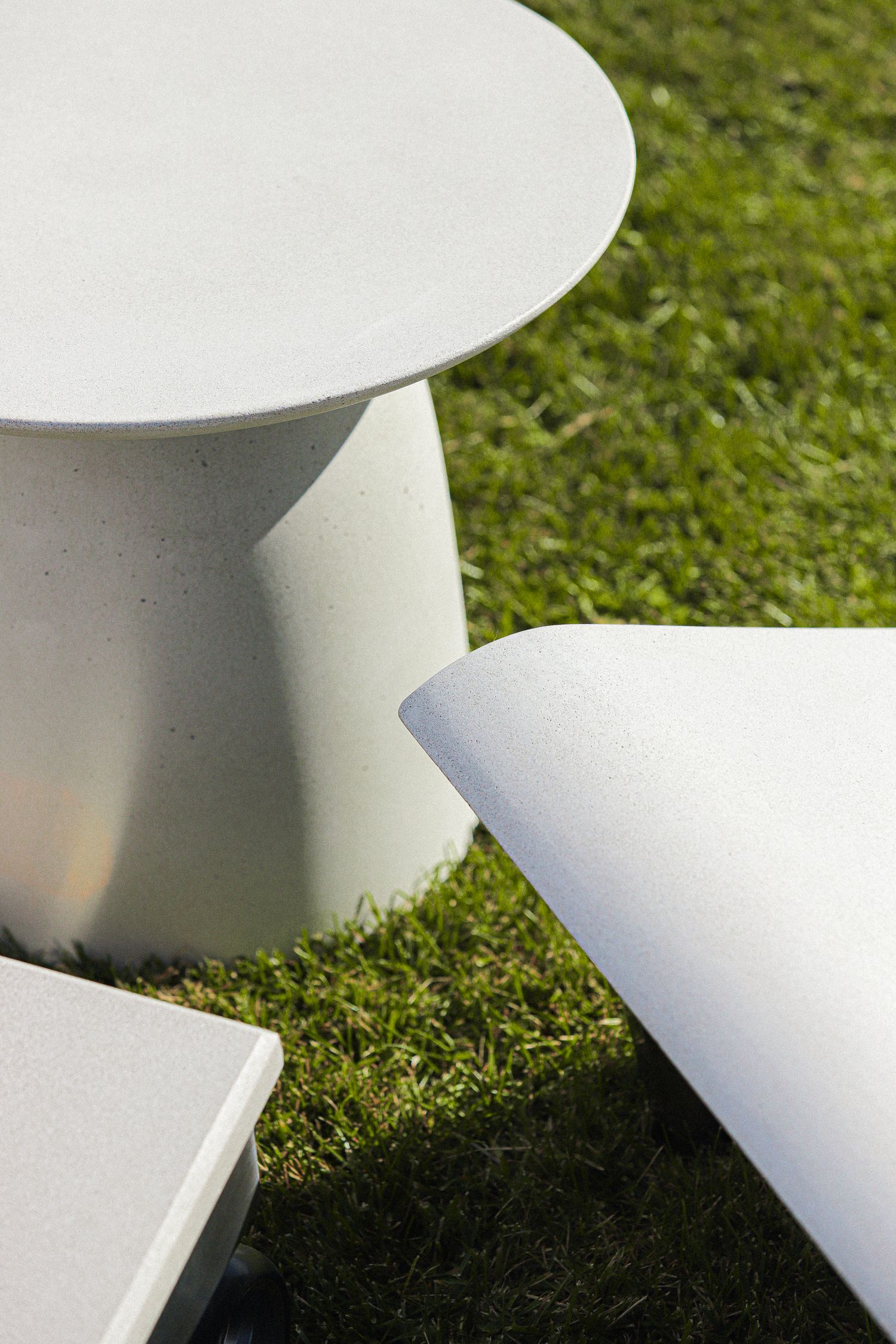 White ceramic bowls cast soft shadows on green grass in an artistic minimalist composition.