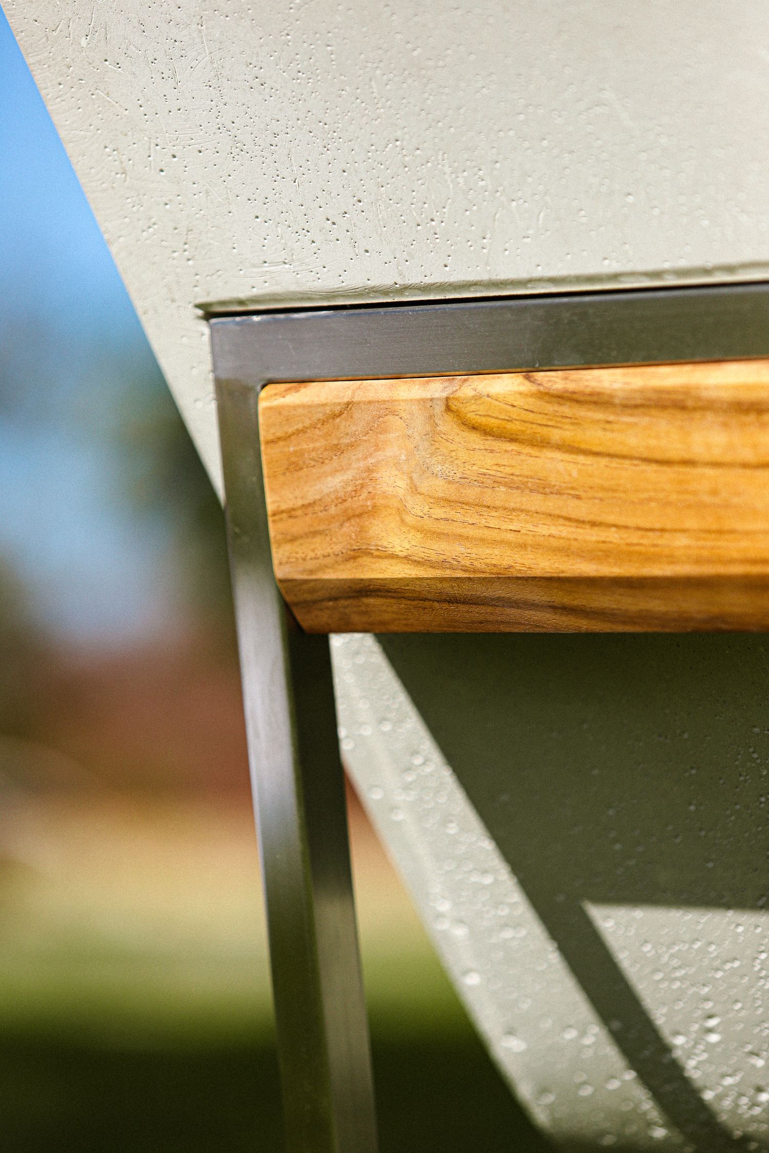 Close-up view of a wooden furniture edge with visible grain pattern against a light background.