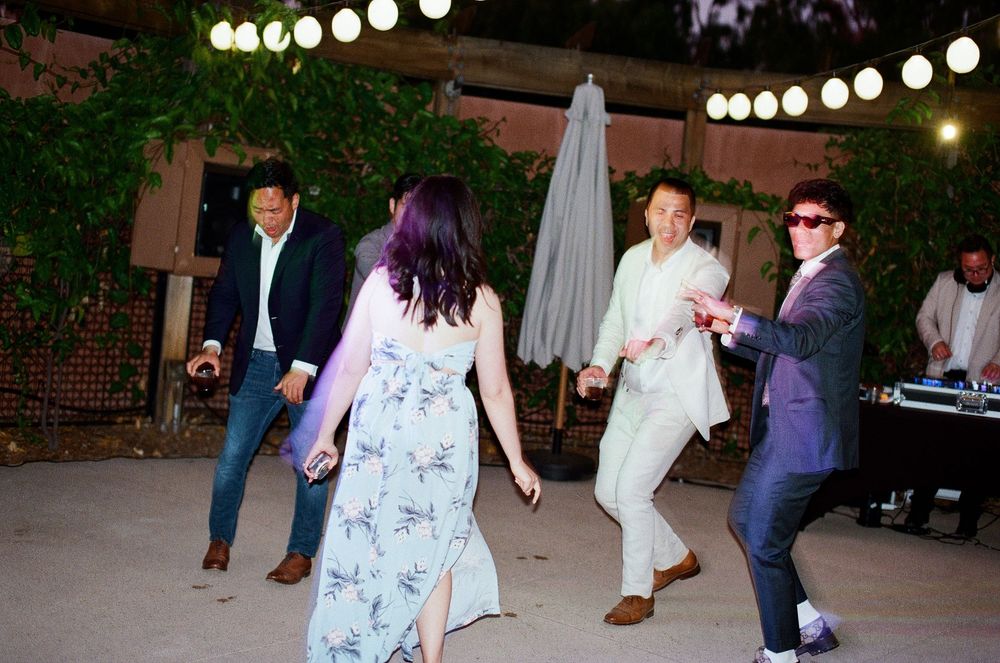 High-energy Orange County film photography of wedding guests dancing at a lively outdoor reception.