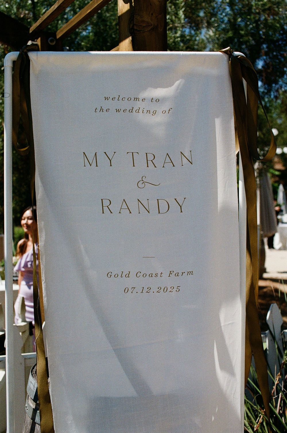 A detailed 35mm film shot of the "Welcome to our Wedding" signage at a lush Orange County garden venue.