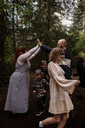 Family dancing and giving high fives together in a woodland forest setting.