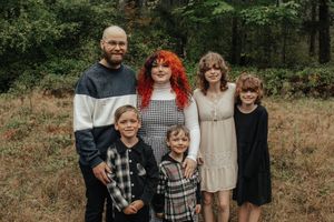 Family of six posing together in an autumn meadow surrounded by fall foliage.