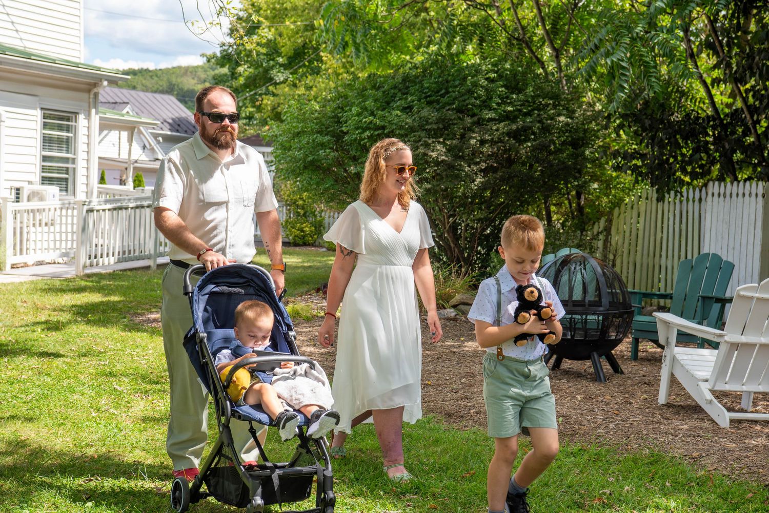 Family enjoying a casual outdoor photoshoot in a backyard garden setting on a sunny day.