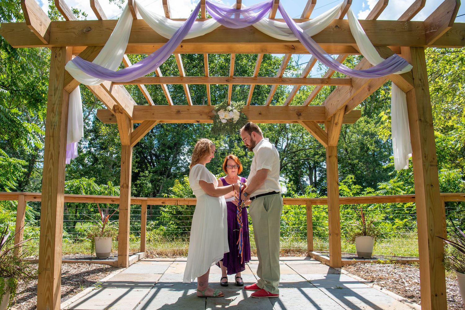 A wooden pergola with decorative beams and string lights creates a romantic outdoor setting in a garden.