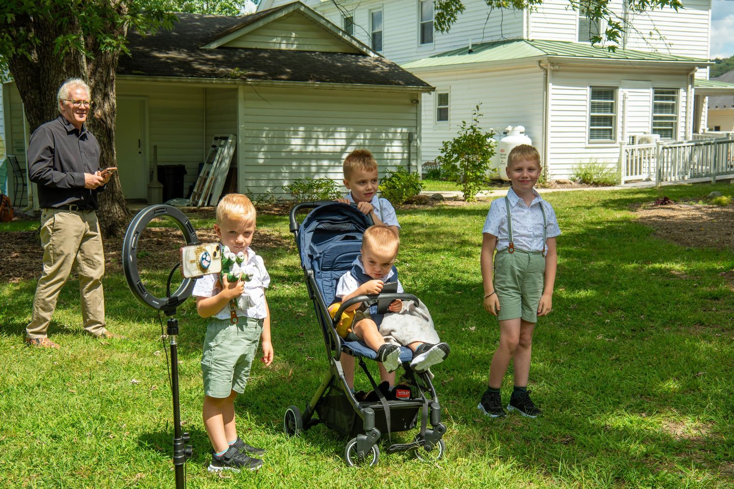 A series of five photos showing a toddler playing and exploring outdoors in a grassy backyard on a sunny day.