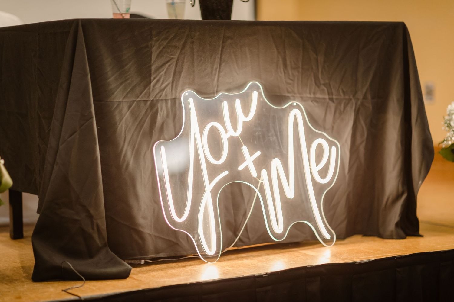 A series of illuminated neon signs glowing against black curtains in a dark room setting.