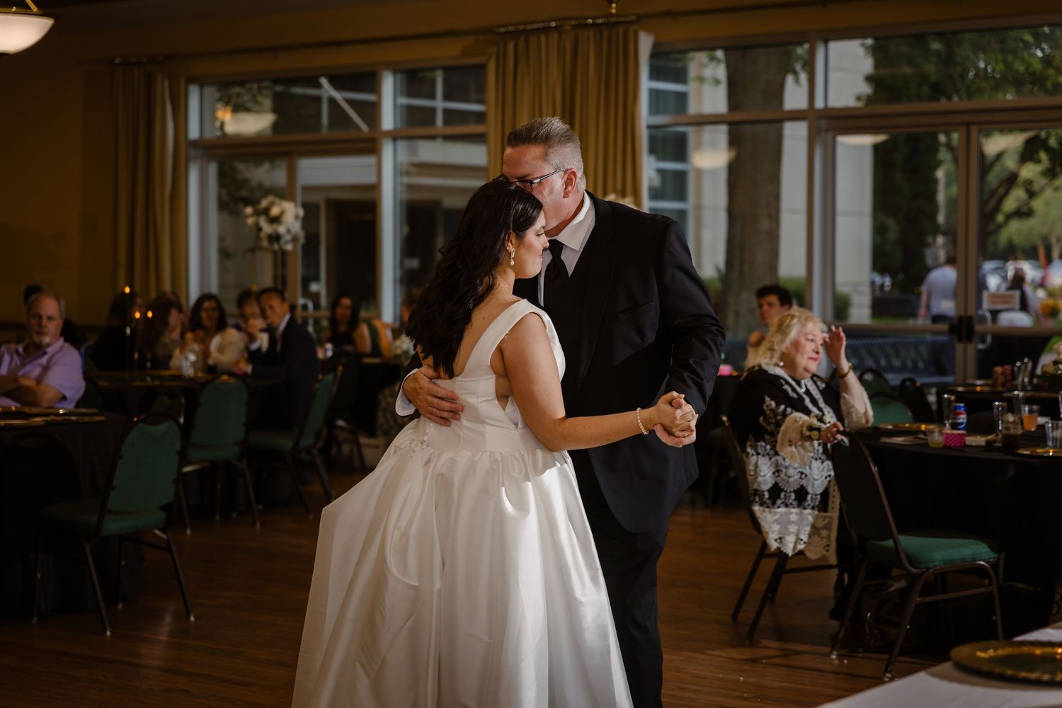A couple dances together during their first dance at an elegant wedding reception in a ballroom.
