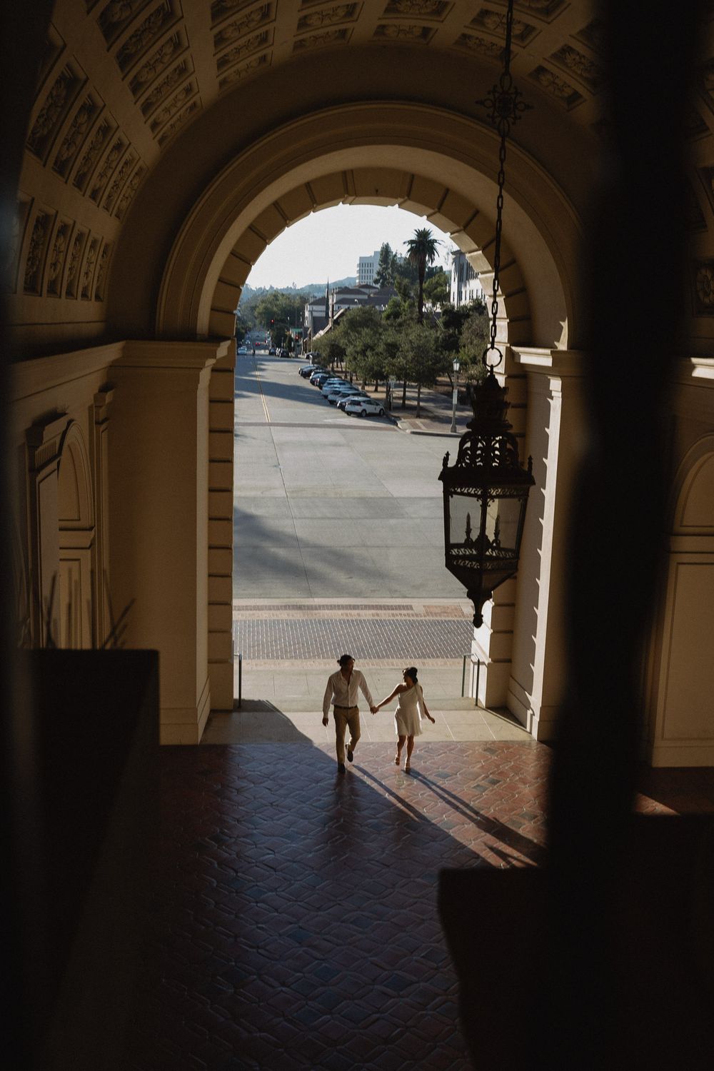 Couple holding hands while walking through City Hall corridor in Los Angeles.