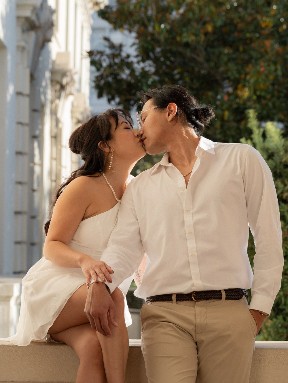 Couple standing small beneath grand arches of Pasadena City Hall