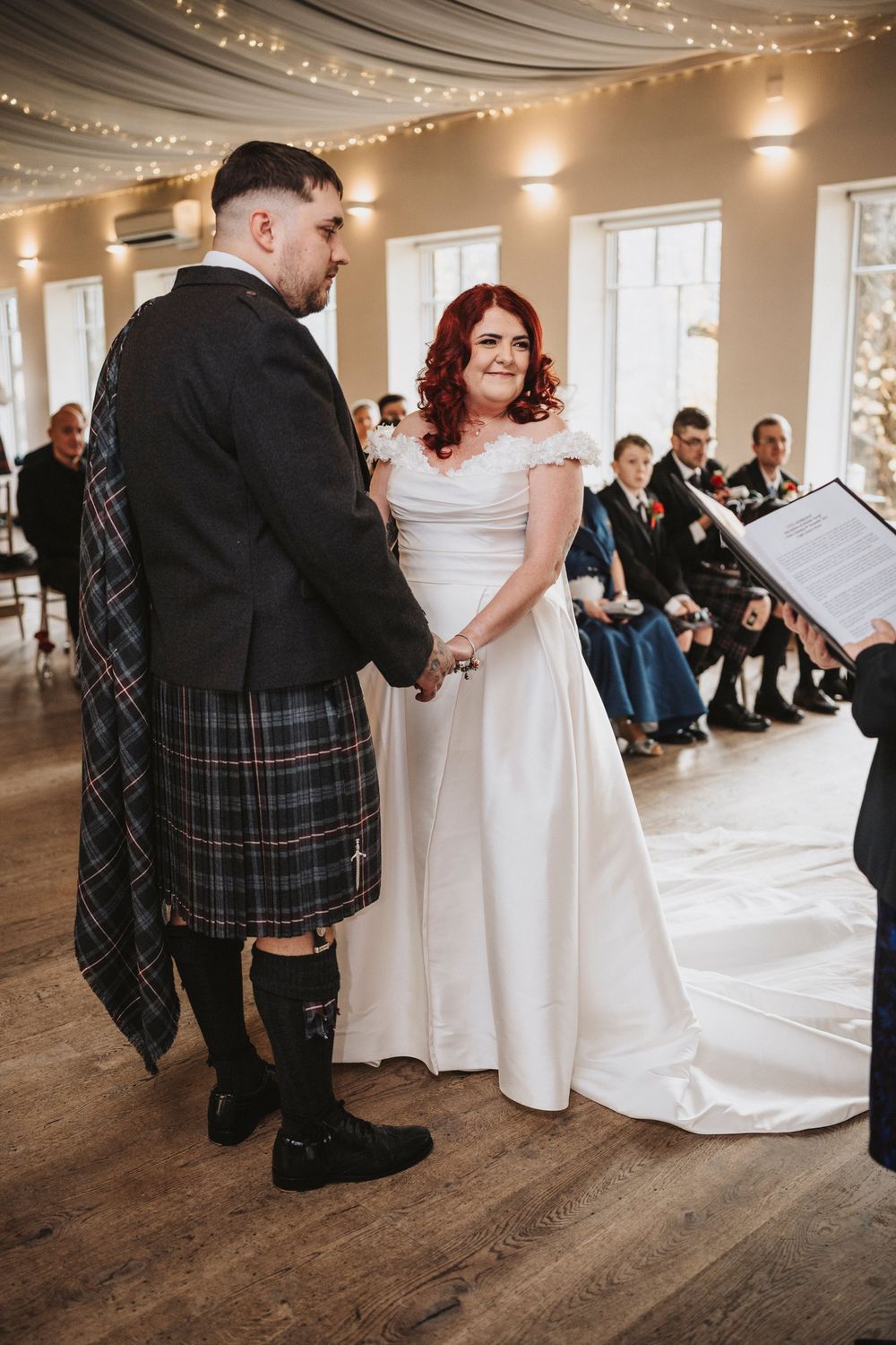 Wedding celebration in elegant venue with string lights and wooden floors during first dance.