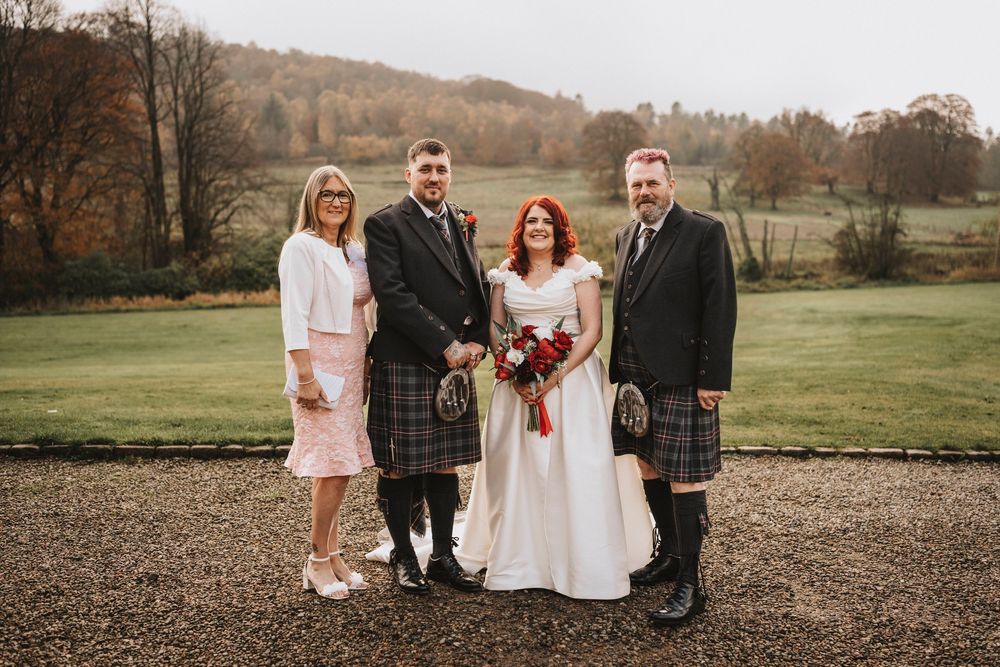Wedding party poses outdoors in autumn with rolling hills in the background.