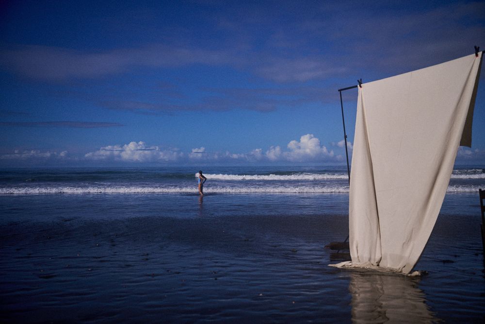Set of a lifestyle photoshoot by photographer Rachael Kershaw at the beach with blue skies and a beige fabric to be used as a backdrop.