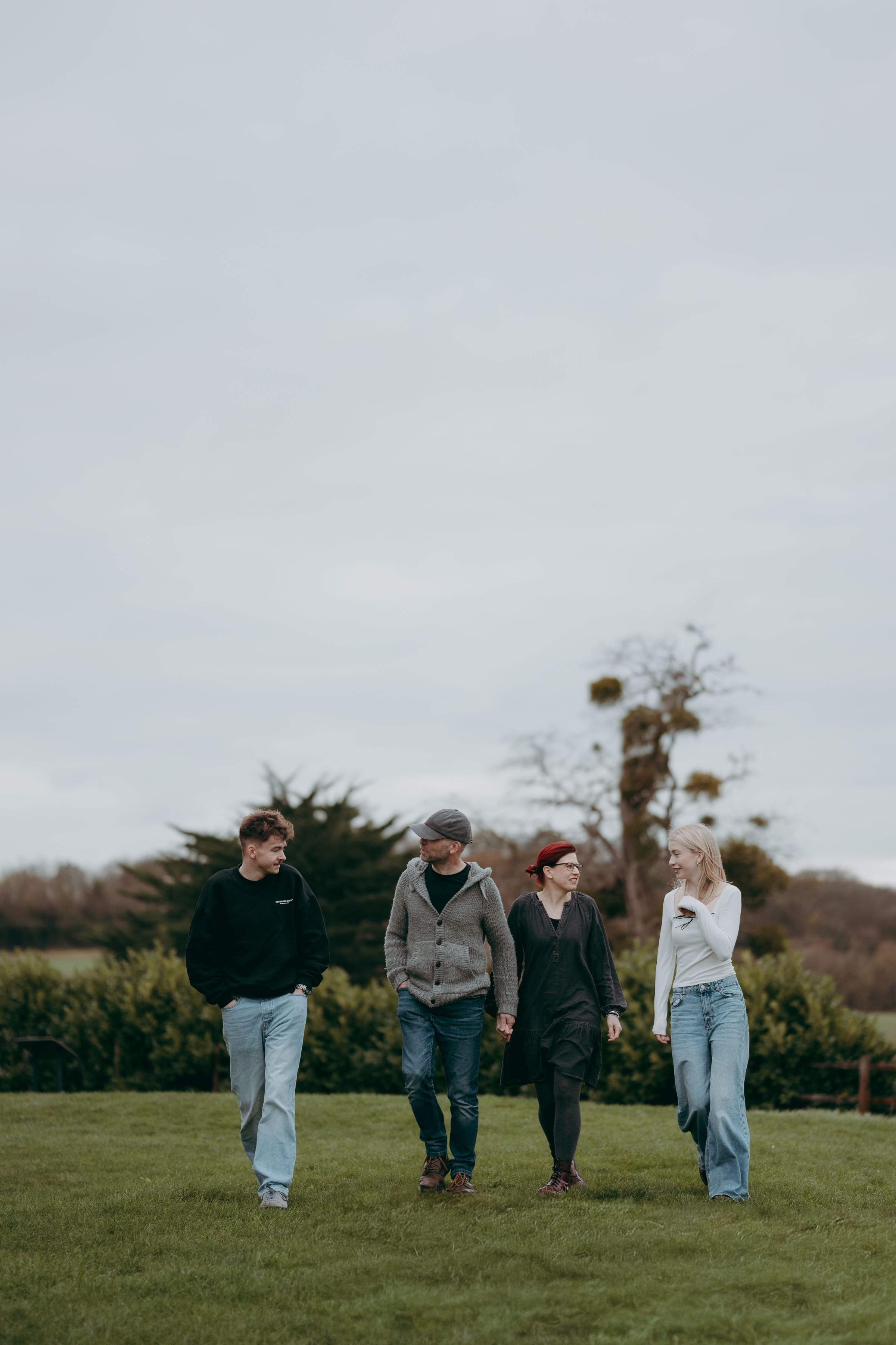 People walking together across a green hillside under cloudy skies.