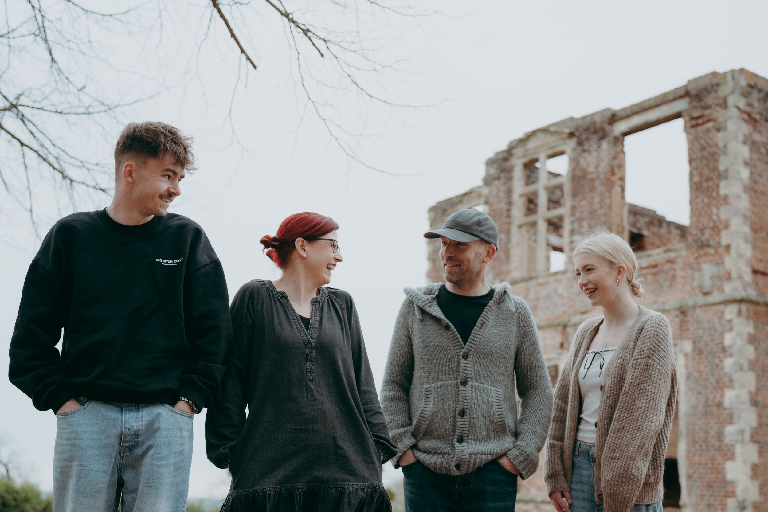 A group of people walk together on a path while engaged in conversation on a cloudy day.