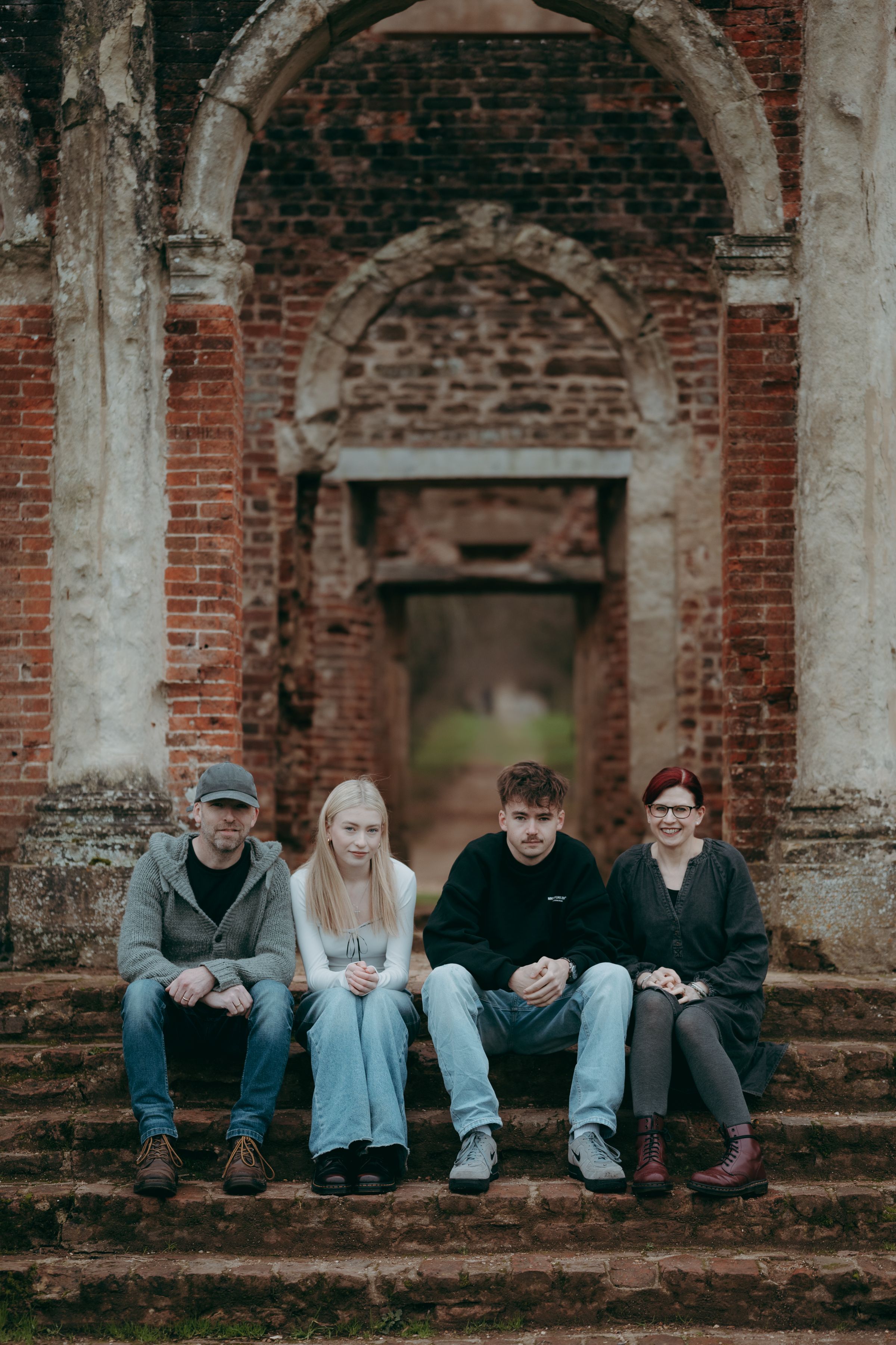 Group of people sitting on old brick ruins in a row during an outdoor photo session.