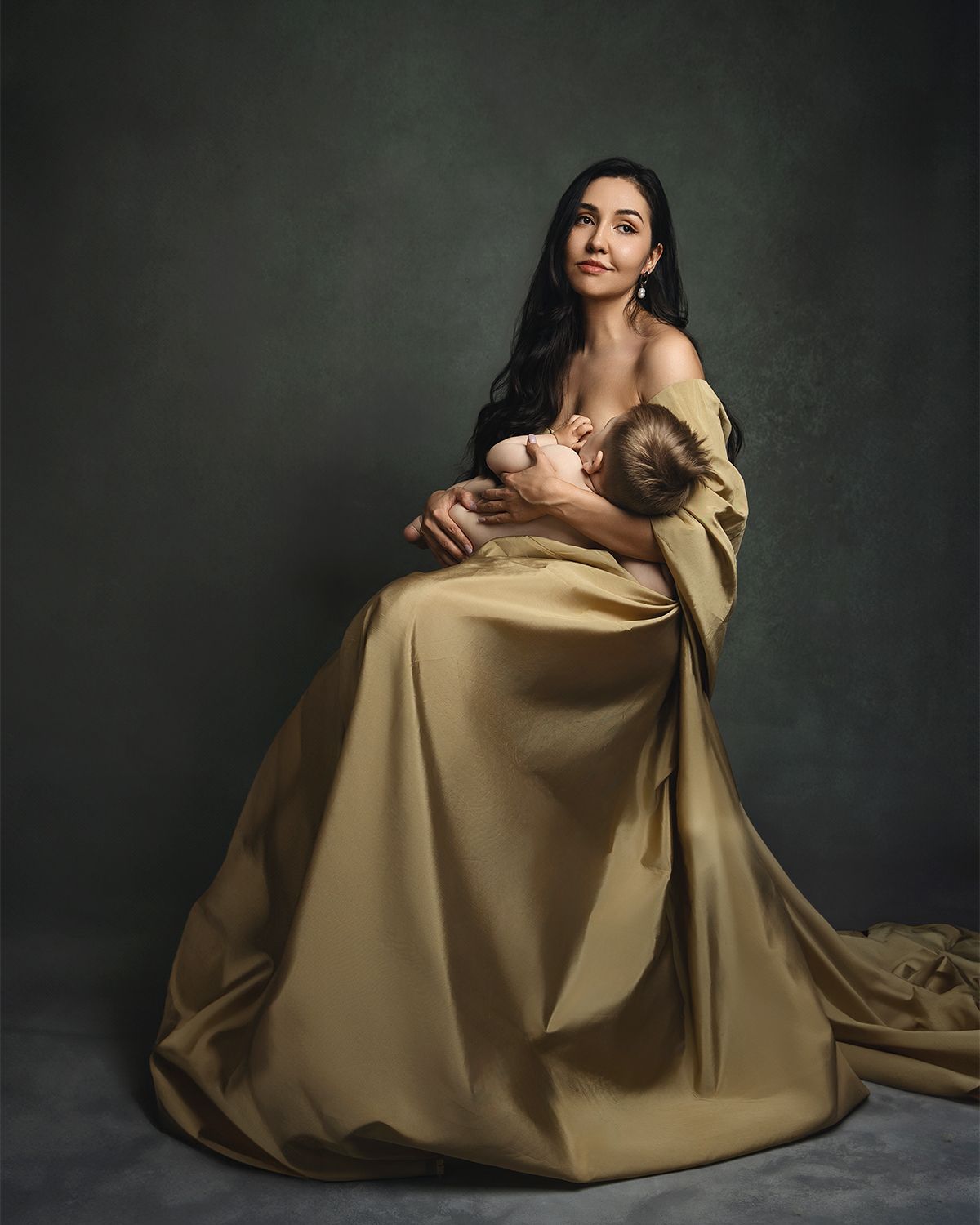 A figure in an elegant gold satin gown poses against a dark backdrop in a classical portrait style.