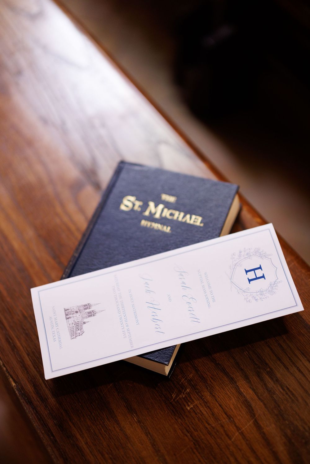 A St. Michael hymnal and wedding program displayed on wooden church pew.