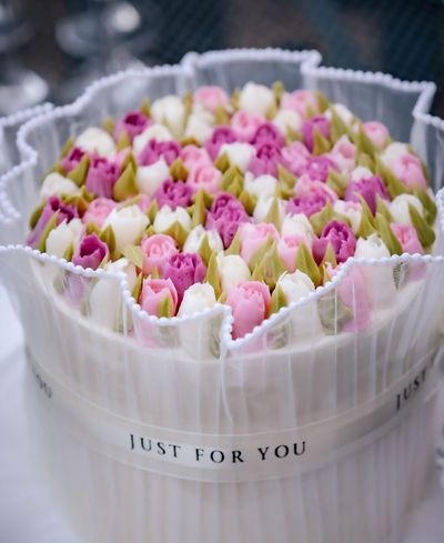 A round gift box labeled Just For You filled with pink, purple, and white tulip buds arranged beautifully.