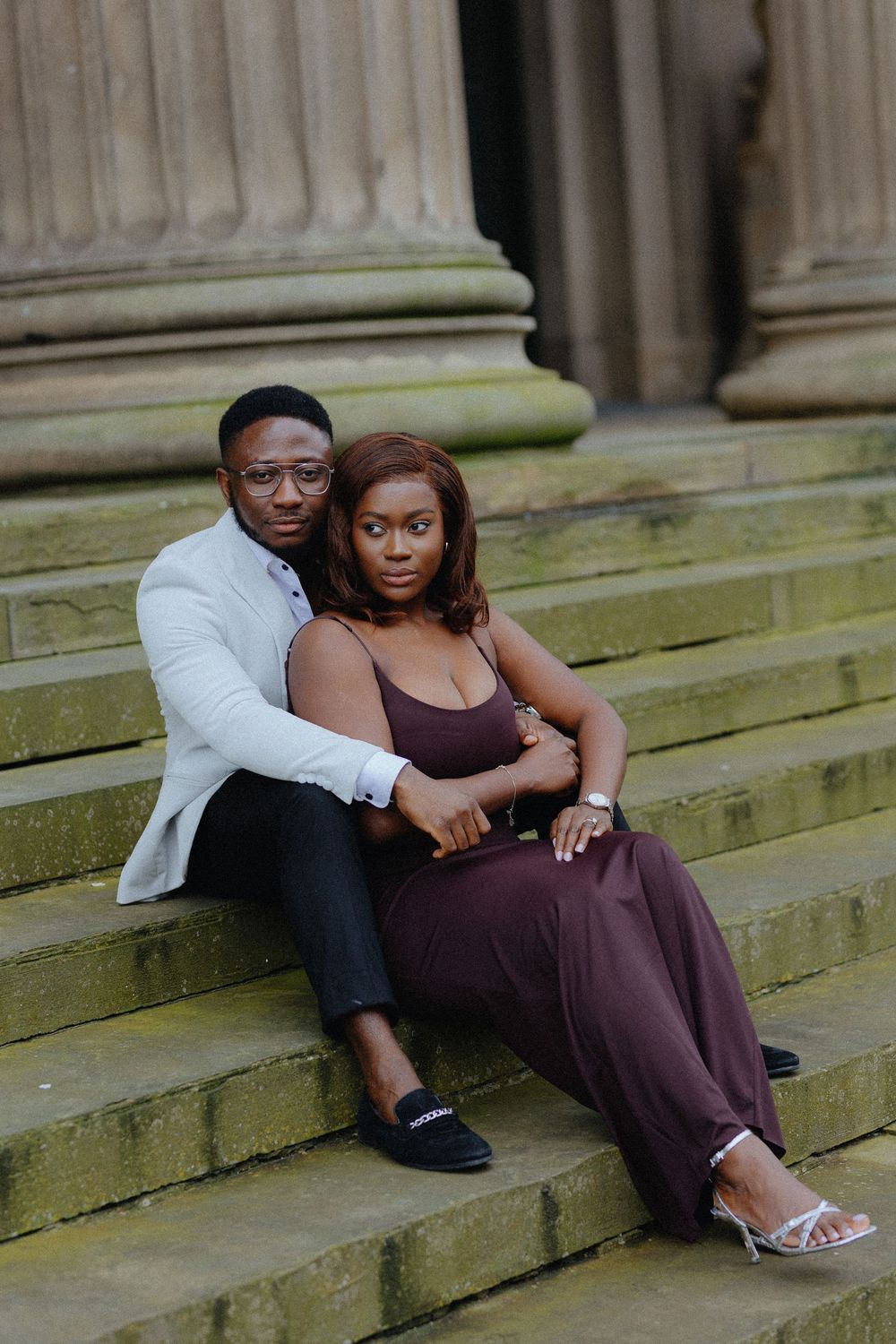 A couple sits intimately together on stone steps during an engagement photoshoot session.