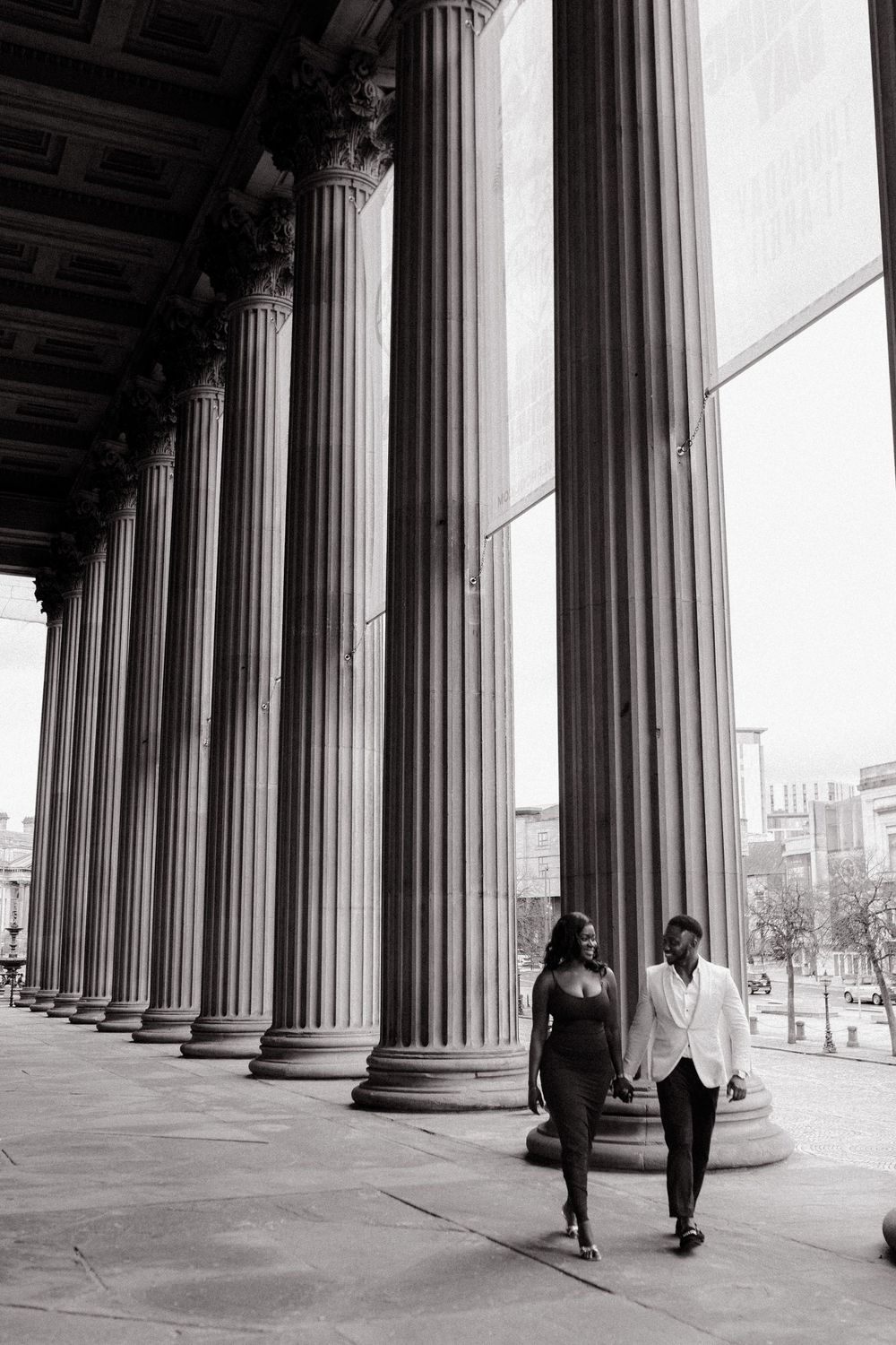 A series of dramatic black and white architectural photographs showing people walking between classical stone columns.