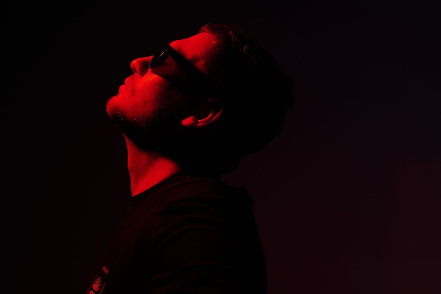 Abstract portrait composition illuminated by vibrant red lighting against a dark background.