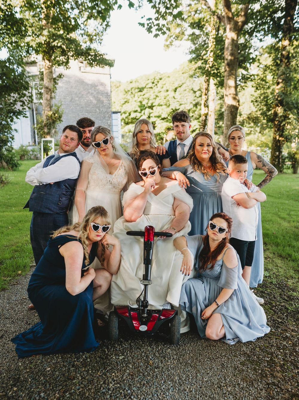 Wedding party members share drinks and laughter while sitting together outdoors on a sunny day.