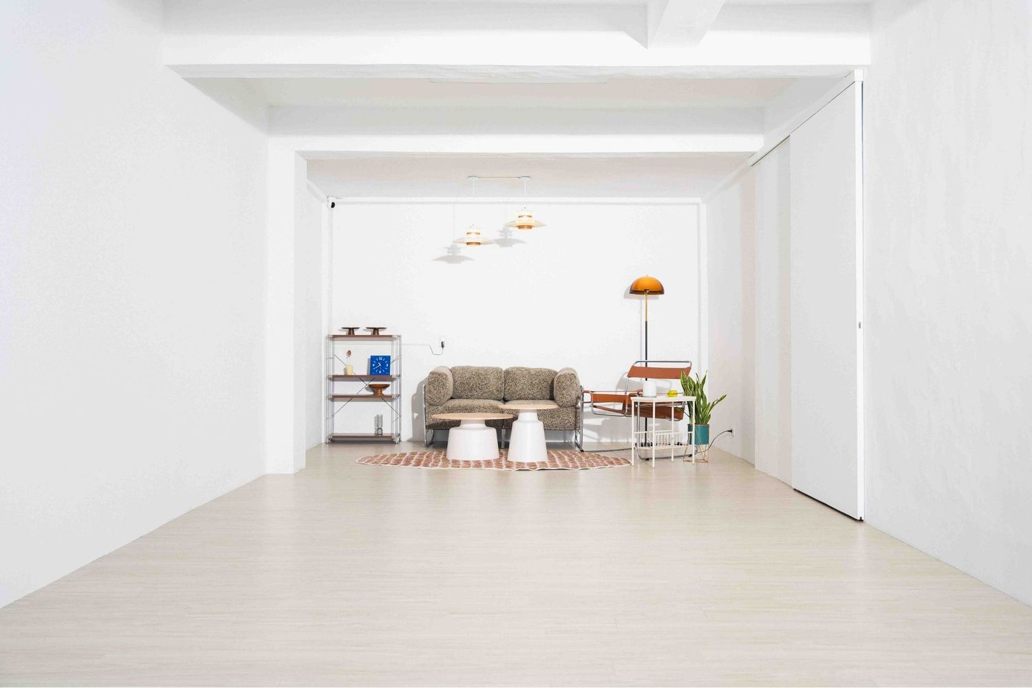 Empty modern hallway with white walls, fluorescent lighting, and plants in the corner of an office or commercial building.